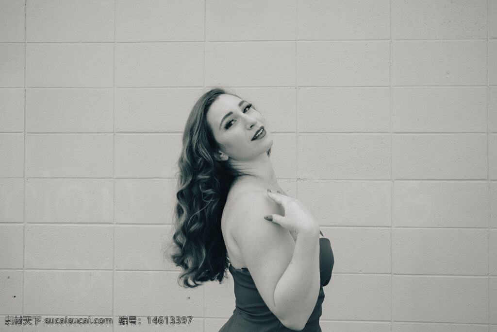 黑白风格 长卷发 美女写真 回眸姿态 人物形象 人像摄影 优雅气质 女性魅力 墙壁背景 单色调 手部动作 曲线美 经典黑白